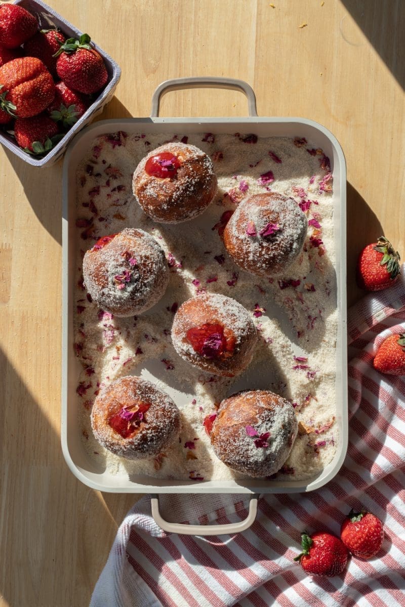 Flat lay of the strawberry rose paczki, sitting in the rose sugar.