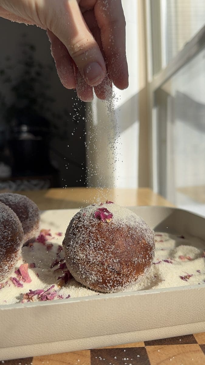 Sprinkling rose sugar on the fried donuts.