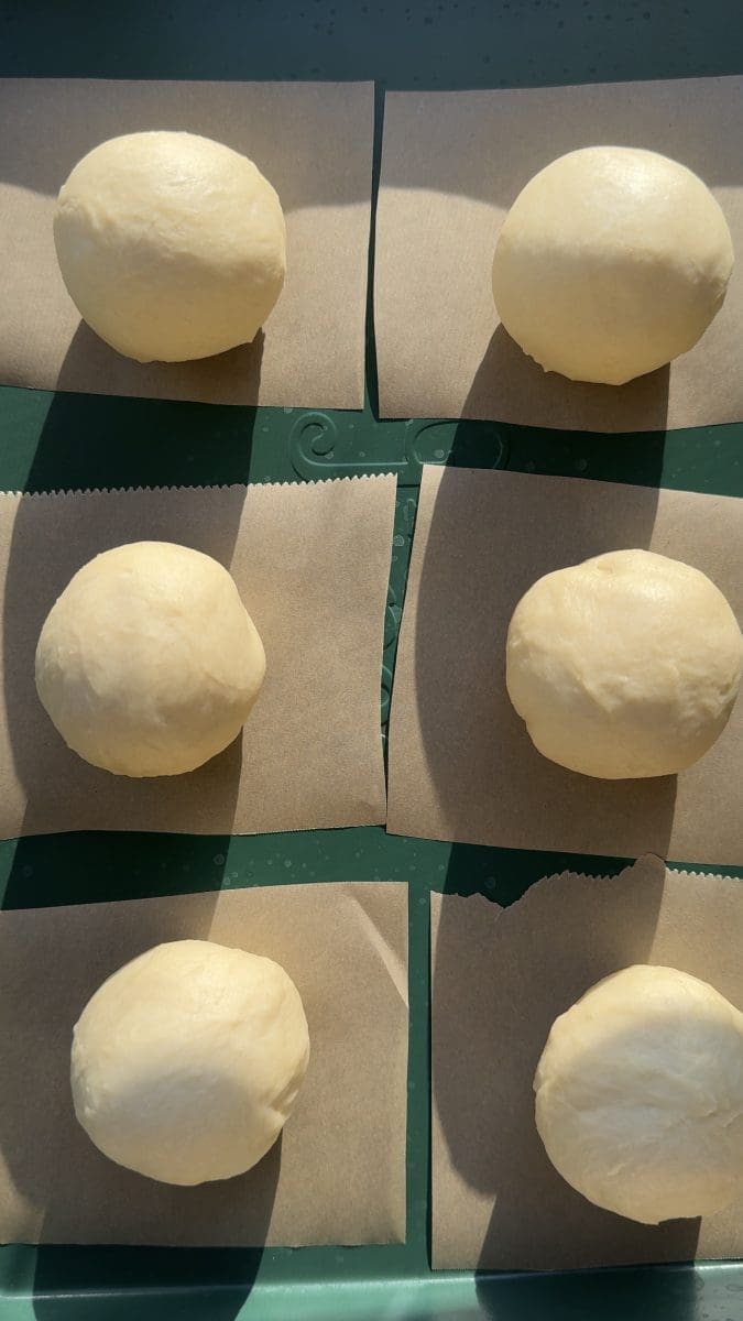 The dough rolled into six balls, on parchment squares.