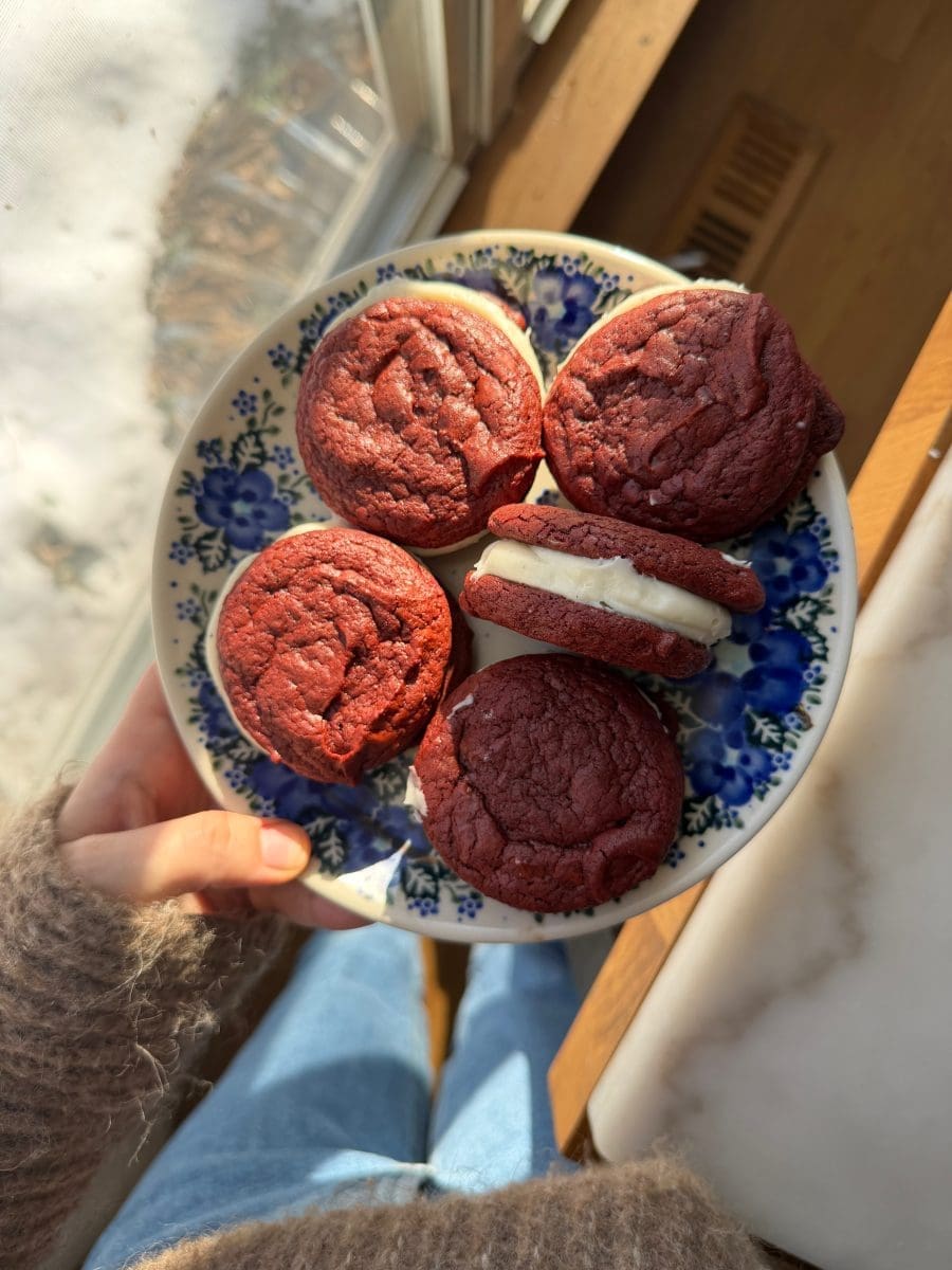 Holding a plate of the red velvet brownie cookie sandwiches.