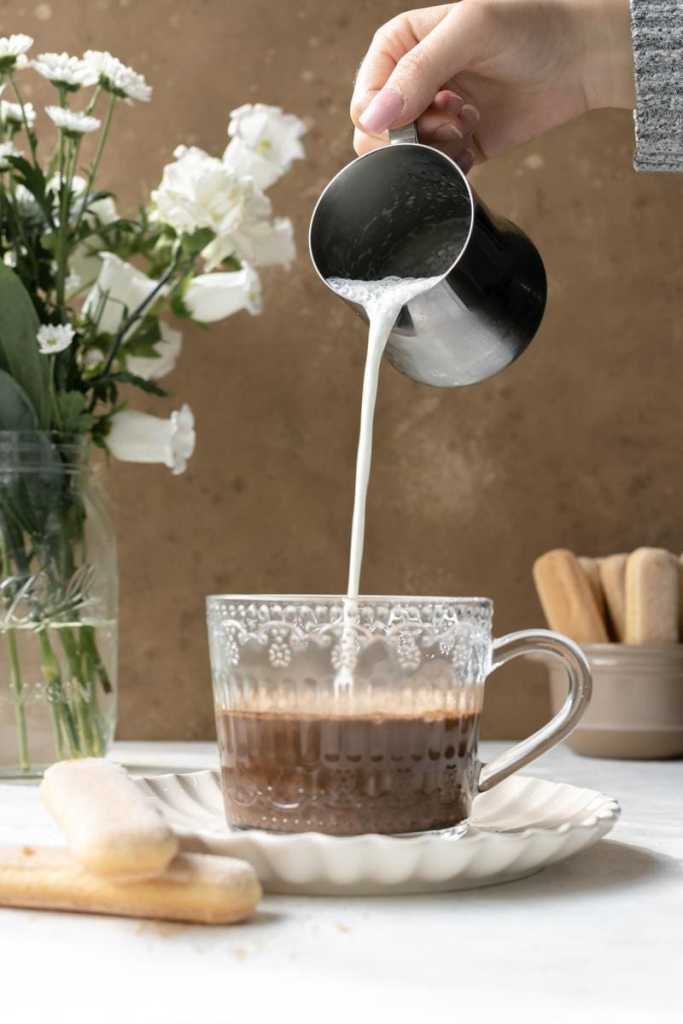 Pouring the frothed milk on top of the espresso.