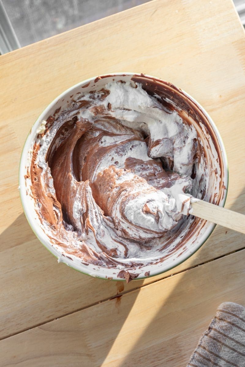 Folding whipped cream into the chocolate mixture.