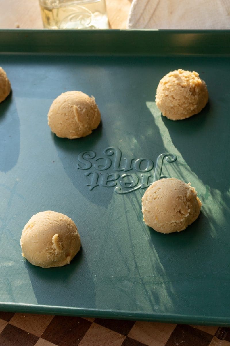 Sugar cookie dough balls on a baking sheet.