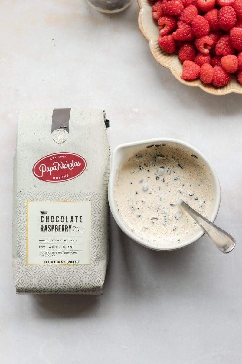 Espresso beans mixed with heavy whipping cream, next to a bag of coffee.