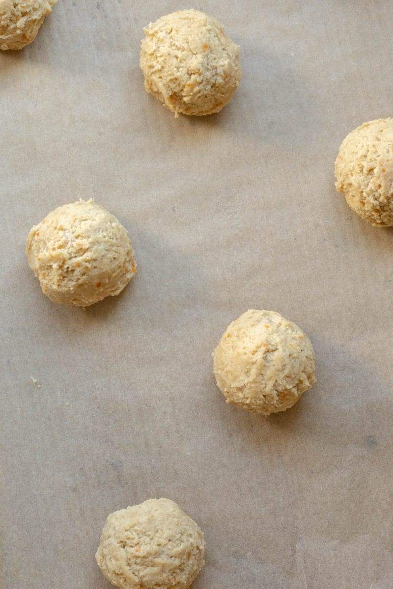 the blood orange cookie dough balls on a parchment lined baking sheet