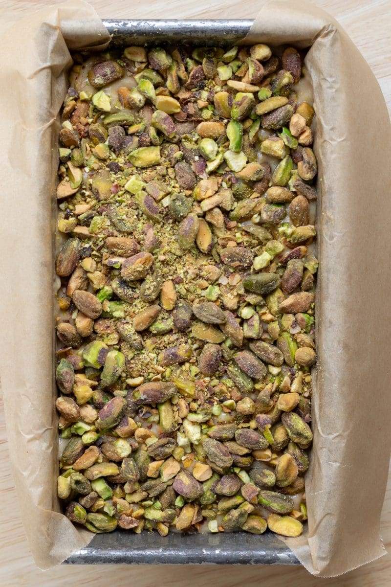 The batter in the loaf pan, topped with pistachios.