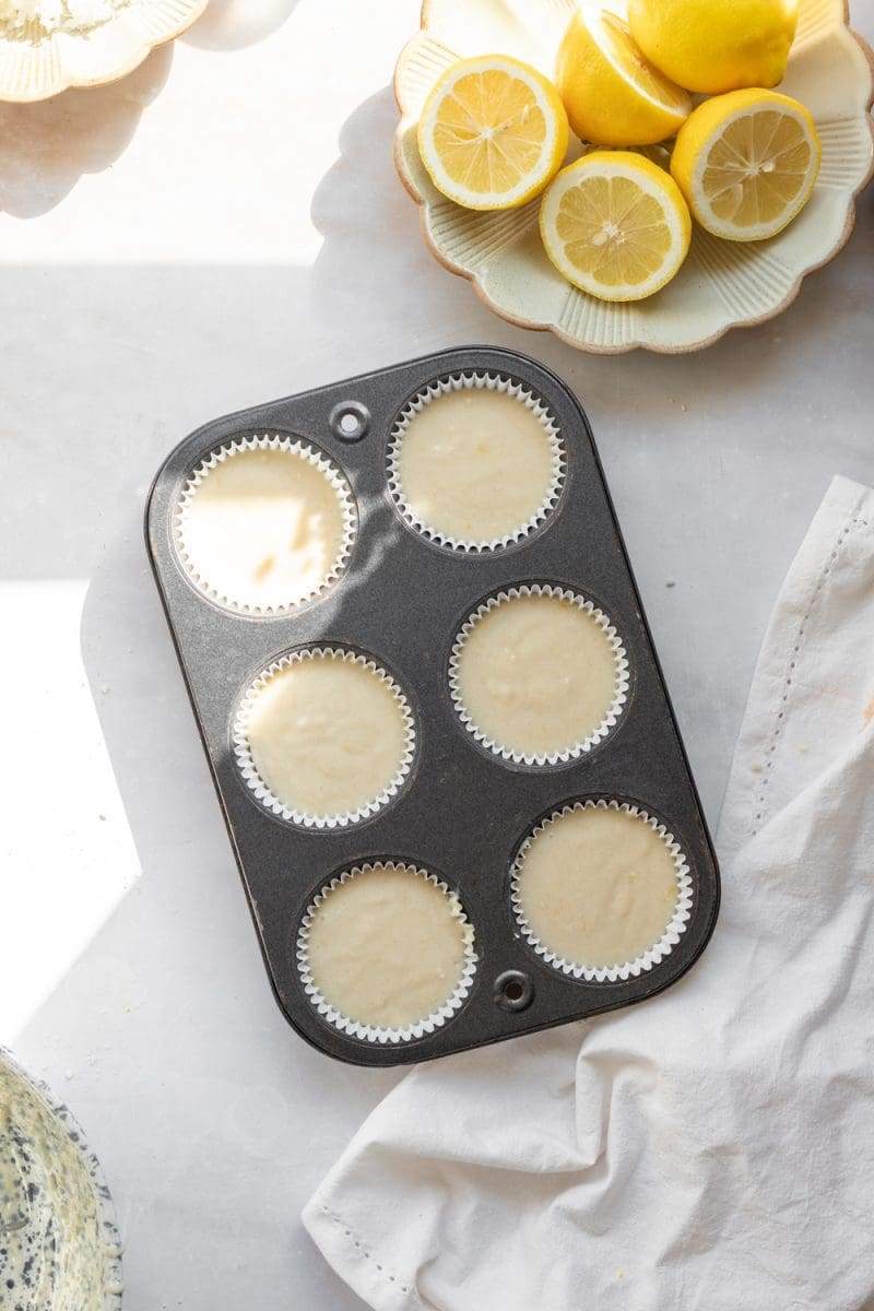 the cupcake batter distributed between six parchment liners