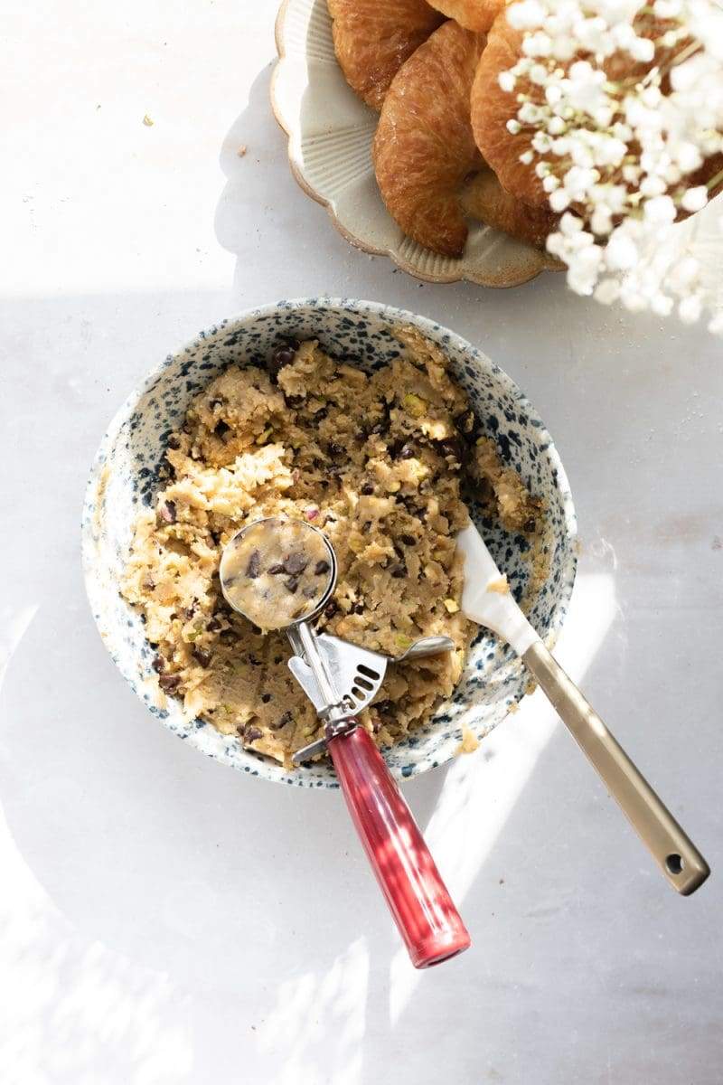the finished cookie dough in a mixing bowl, with a scoop of cookie dough scooped from it.