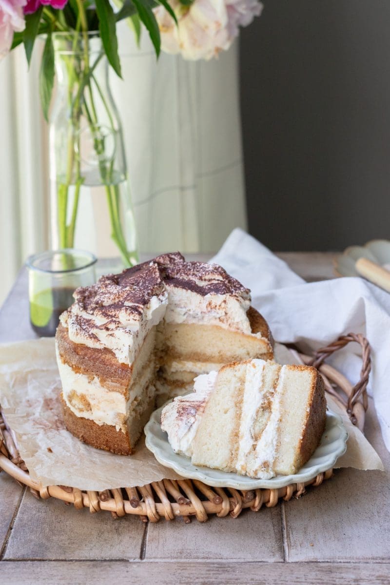 A slice of the tiramisu cake laying in front of the sliced cake.