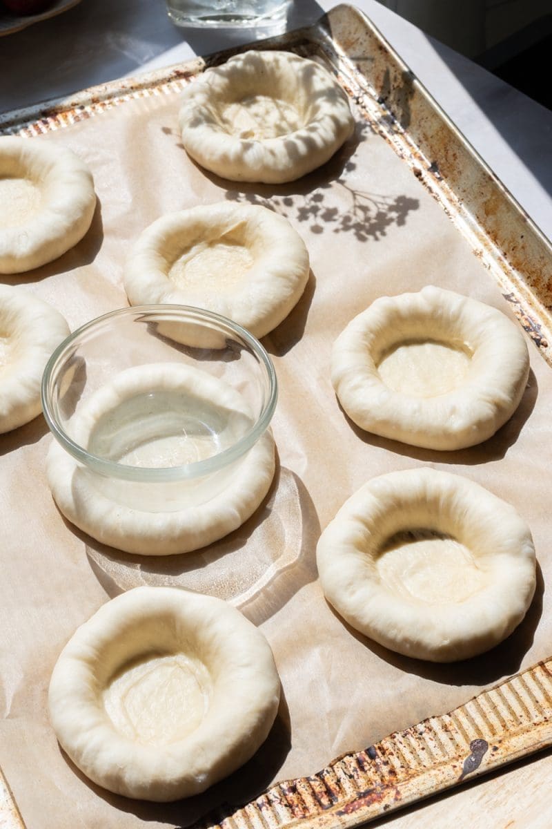 The dough balls with a divot in them on the baking tray.