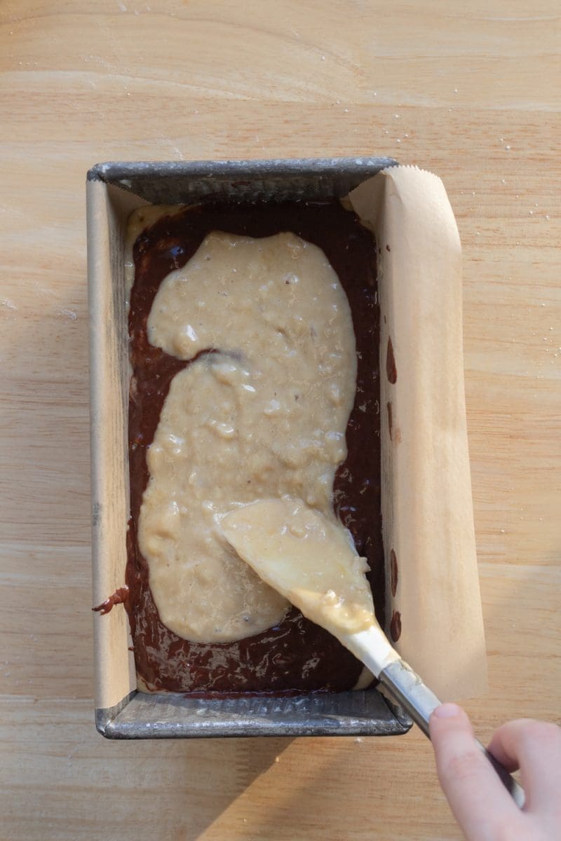 Layering the banana and chocolate batter in a loaf pan.