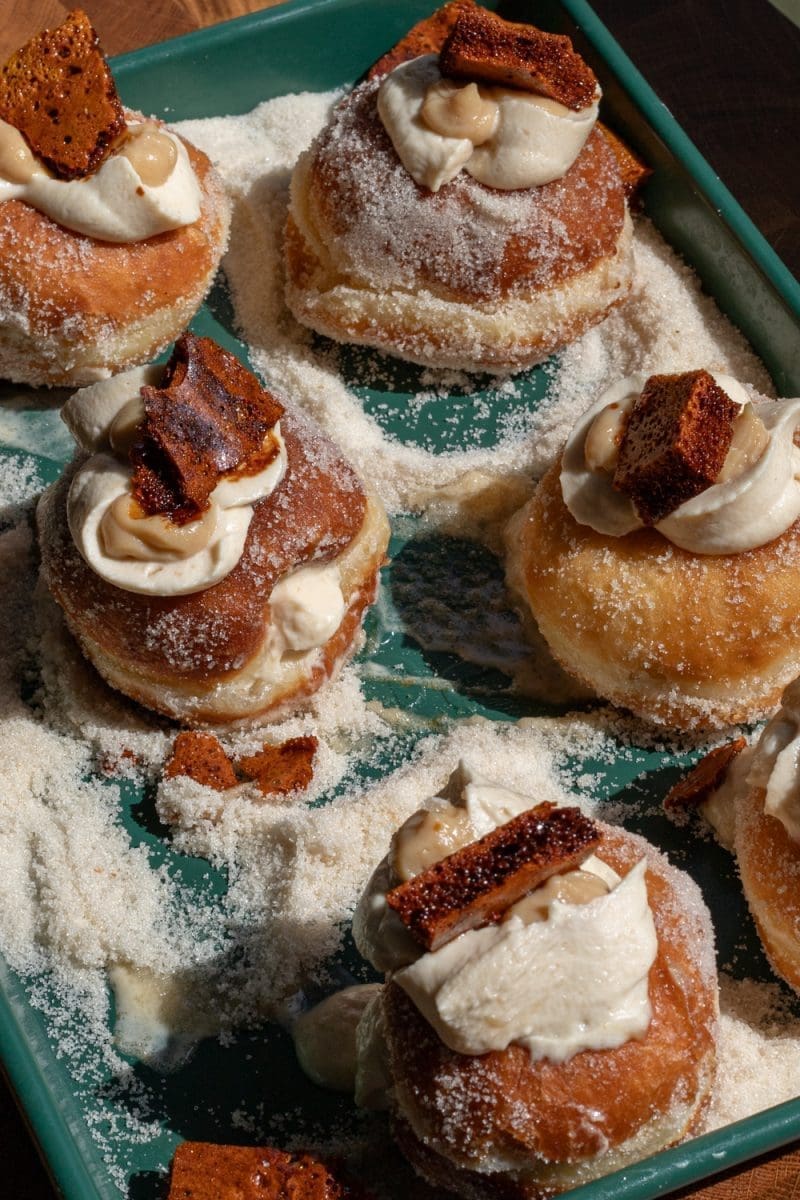 Burnt honey brioche donuts assembled on a baking tray.