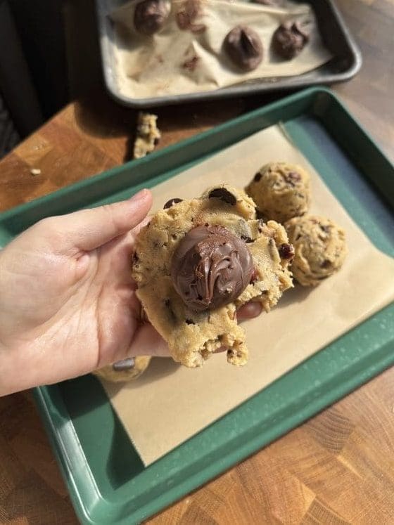 A frozen piece of nutella on top of a flattened piece of cookie dough.