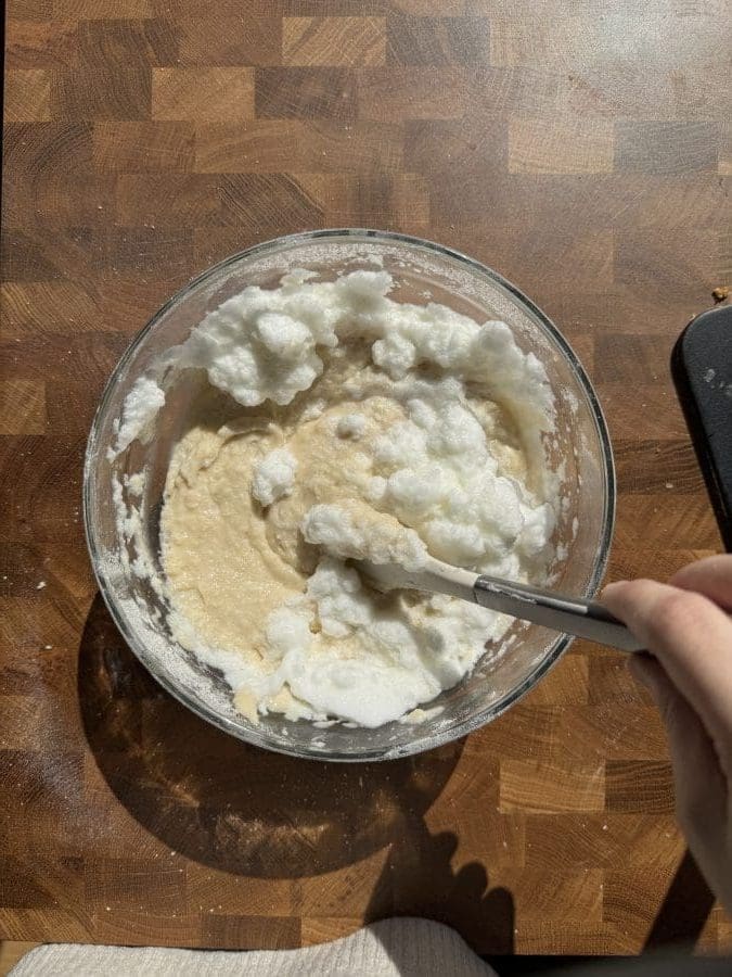 Folding whipped egg whites into the batter.