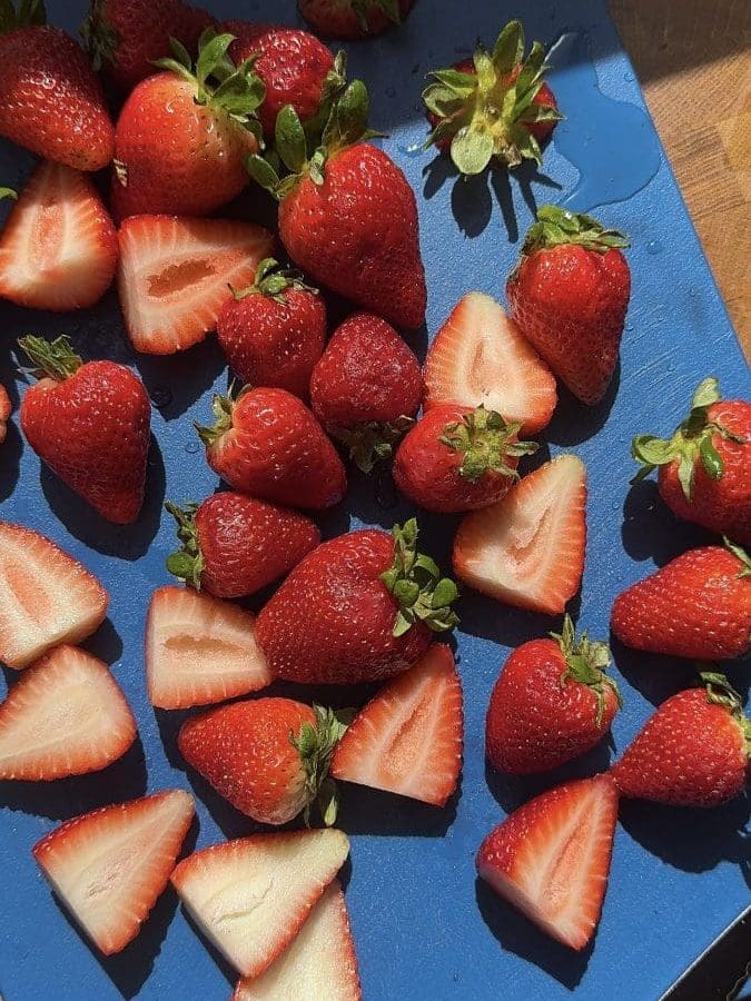 Strawberries chopped on a cutting board.