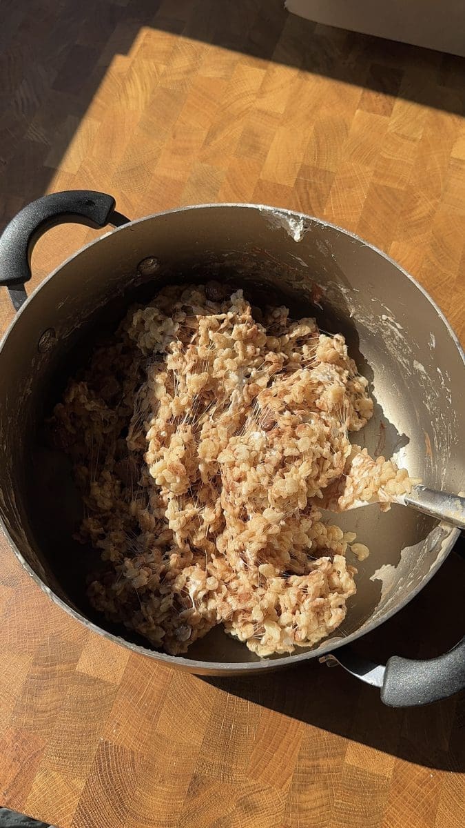 Folding the cereal into the melted butter and marshmallow mixture.