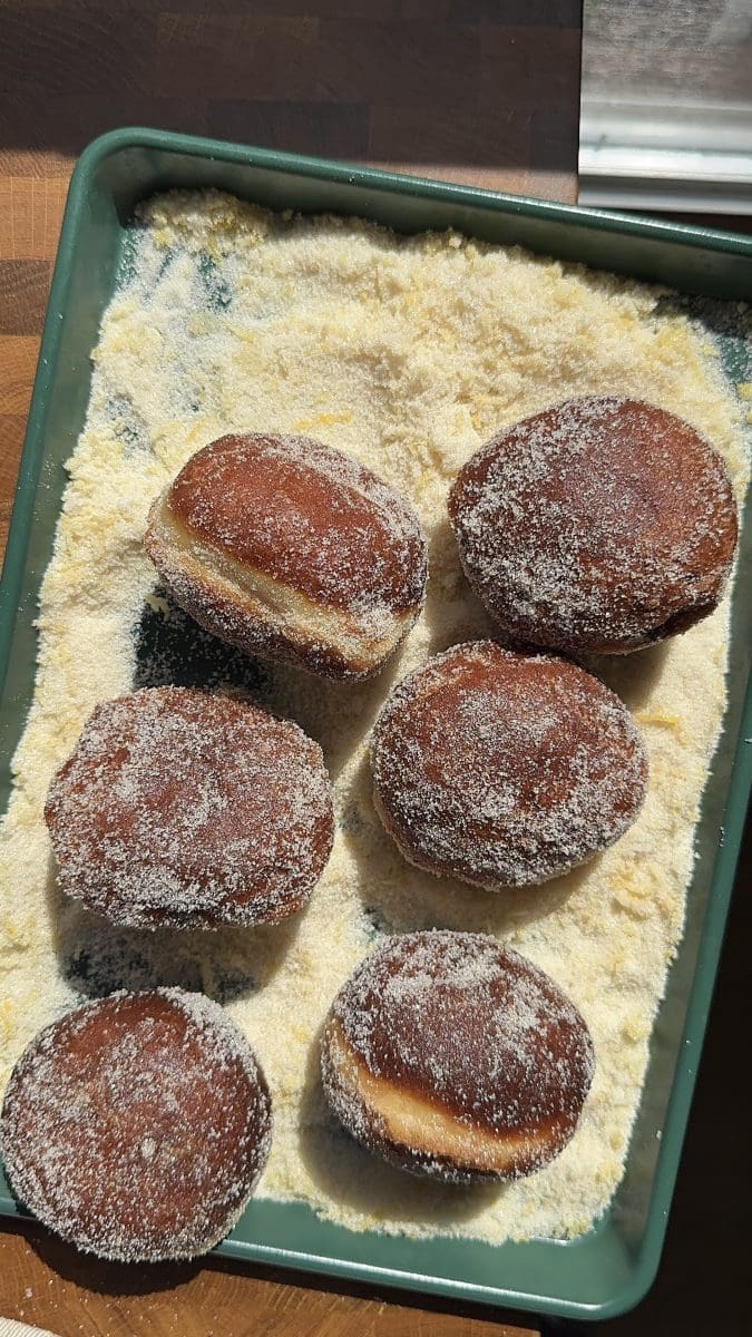 Coating the donuts in lemon sugar.